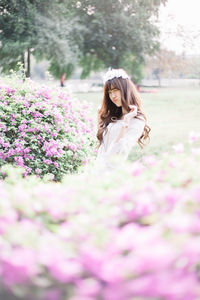 Portrait of woman standing by blooming flowers in park