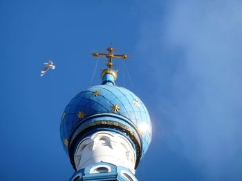 Low angle view of cross and building against blue sky