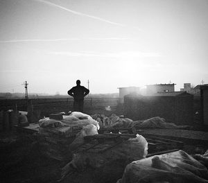 Man sitting in city against sky