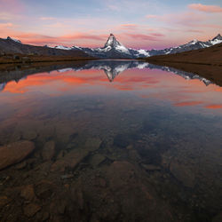 Scenic view of lake and snowcapped mountains against sky during sunset