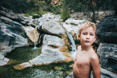 Portrait of shirtless boy on rock