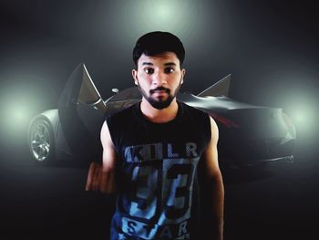 Portrait of young man standing against black background