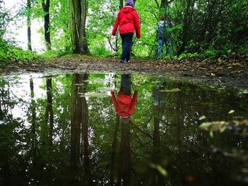 Rear view of woman walking by puddle in forest