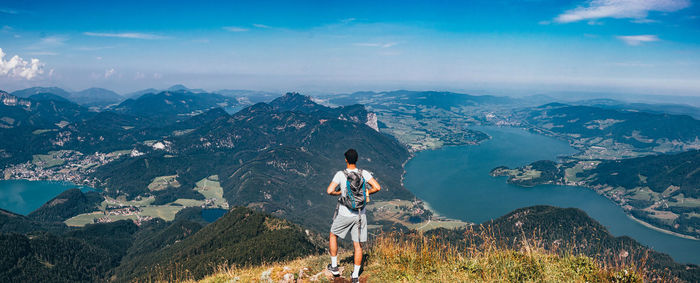 Rear view of man standing on mountain against sky