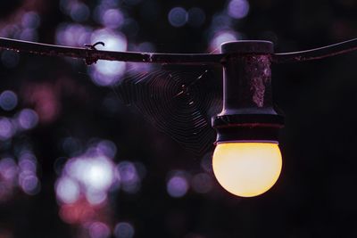 Low angle view of illuminated lighting equipment hanging at night