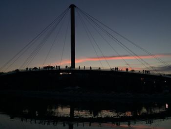 Silhouette suspension bridge against sky during sunset