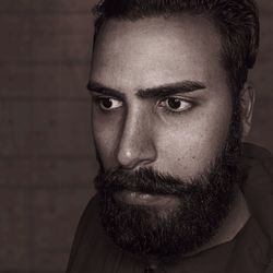 Close-up of serious young man looking away while standing against wall