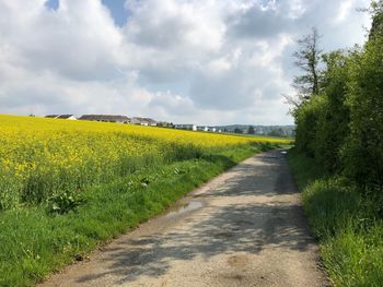 Road amidst field against sky