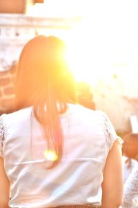 Rear view of woman standing against sun
