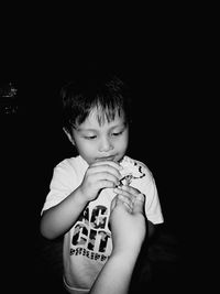 Portrait of cute boy holding camera over black background