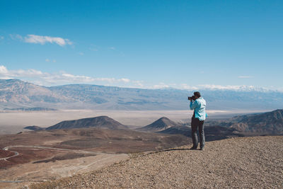 Rear view of man standing on mountain against sky