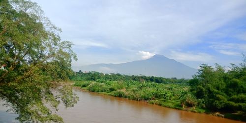 Scenic view of river by mountains against sky