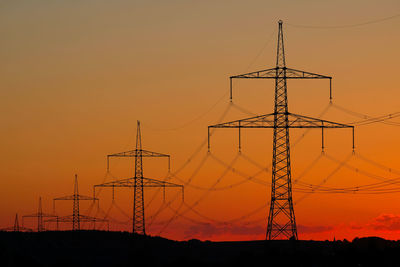 Low angle view of silhouette electricity pylon against romantic sky