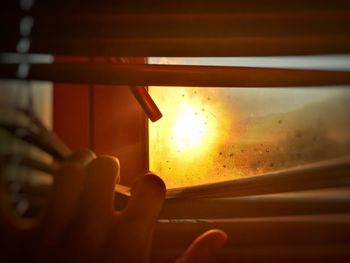 Close-up of hand on glass window during sunset