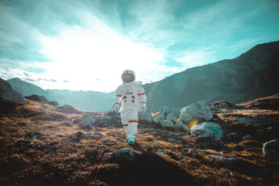 Rear view of man standing on mountain against sky