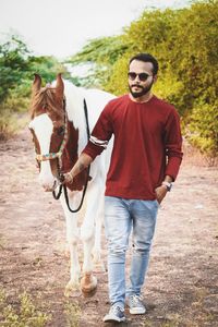 Portrait of man standing with horse on field