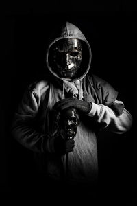 Portrait of a person wearing mask against black background