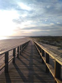 Jetty leading towards sea against sky during sunset