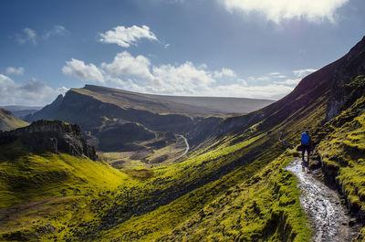 Man walking on mountain against cloudy sky