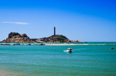 Boat sailing in sea against clear blue sky