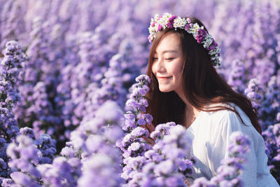Beautiful woman wearing tiara smelling flowers
