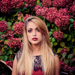 Portrait of young woman standing against flowering plant