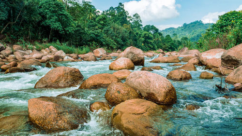 Scenic view of rocks by river against sky