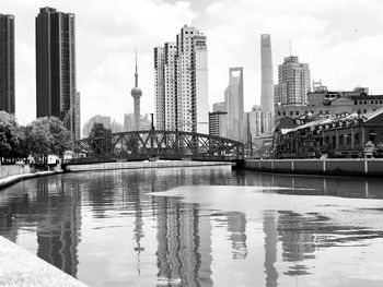 Modern buildings by river against sky in city
