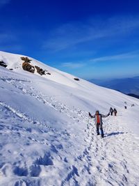 People on snow covered mountain against sky