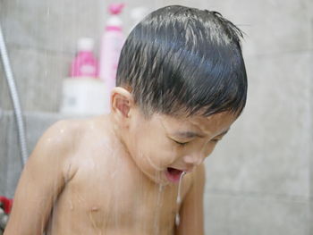 Close-up of shirtless boy taking bath in bathroom