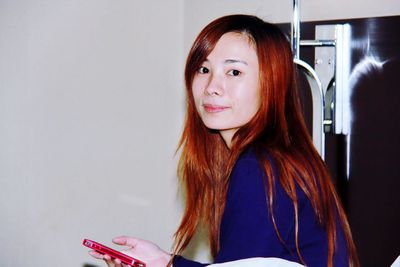 Portrait of young woman using mobile phone while sitting at home