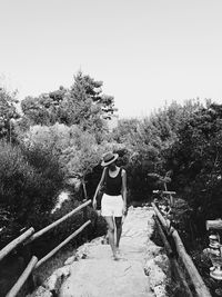 Rear view of woman standing on footbridge against clear sky