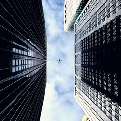 Directly below shot of modern buildings and helicopter against cloudy sky