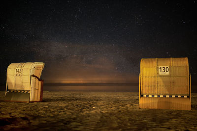 Beach chair on beach against sky at night