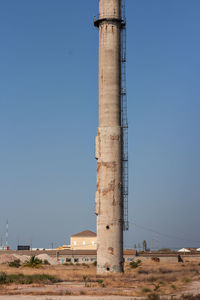 Old factory on field against clear blue sky