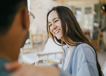 Smiling young woman talking with man sitting in patio