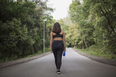 Rear view of woman on road amidst trees