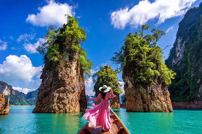 Woman standing on rock by sea against sky