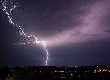 Lightning over illuminated cityscape against dramatic sky