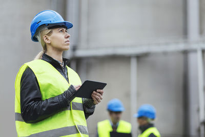 Female worker using digital tablet while looking away at factory