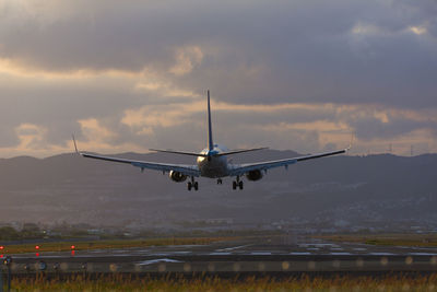 Airplane flying in sky at sunset