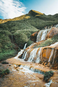 Scenic view of waterfall against sky