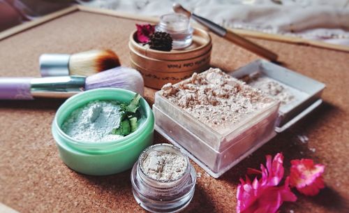 Composition of cosmetics clay and loose powder on wooden background.