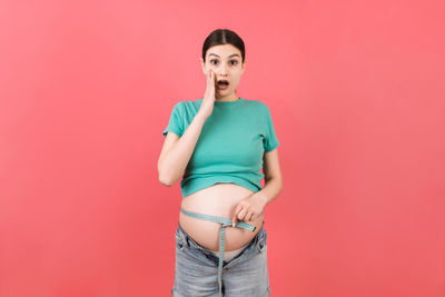 Portrait of young woman against red background