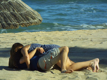 Close-up of romantic couple lying at beach by sea