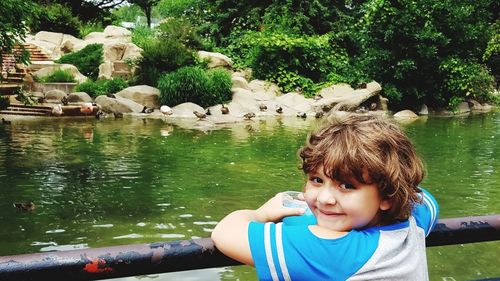 Portrait of boy by lake against trees