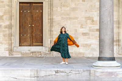 Woman in green dress and orange scarf exploring istanbul on vacation