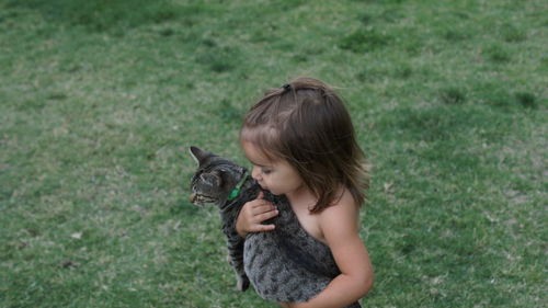 Girl holding cat standing on grass