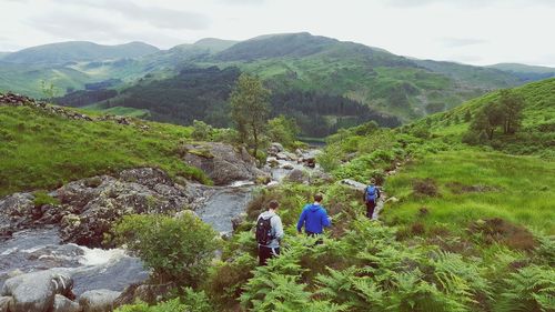 Men hiking by stream at mountain