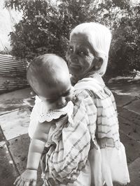 Portrait of senior woman carrying granddaughter